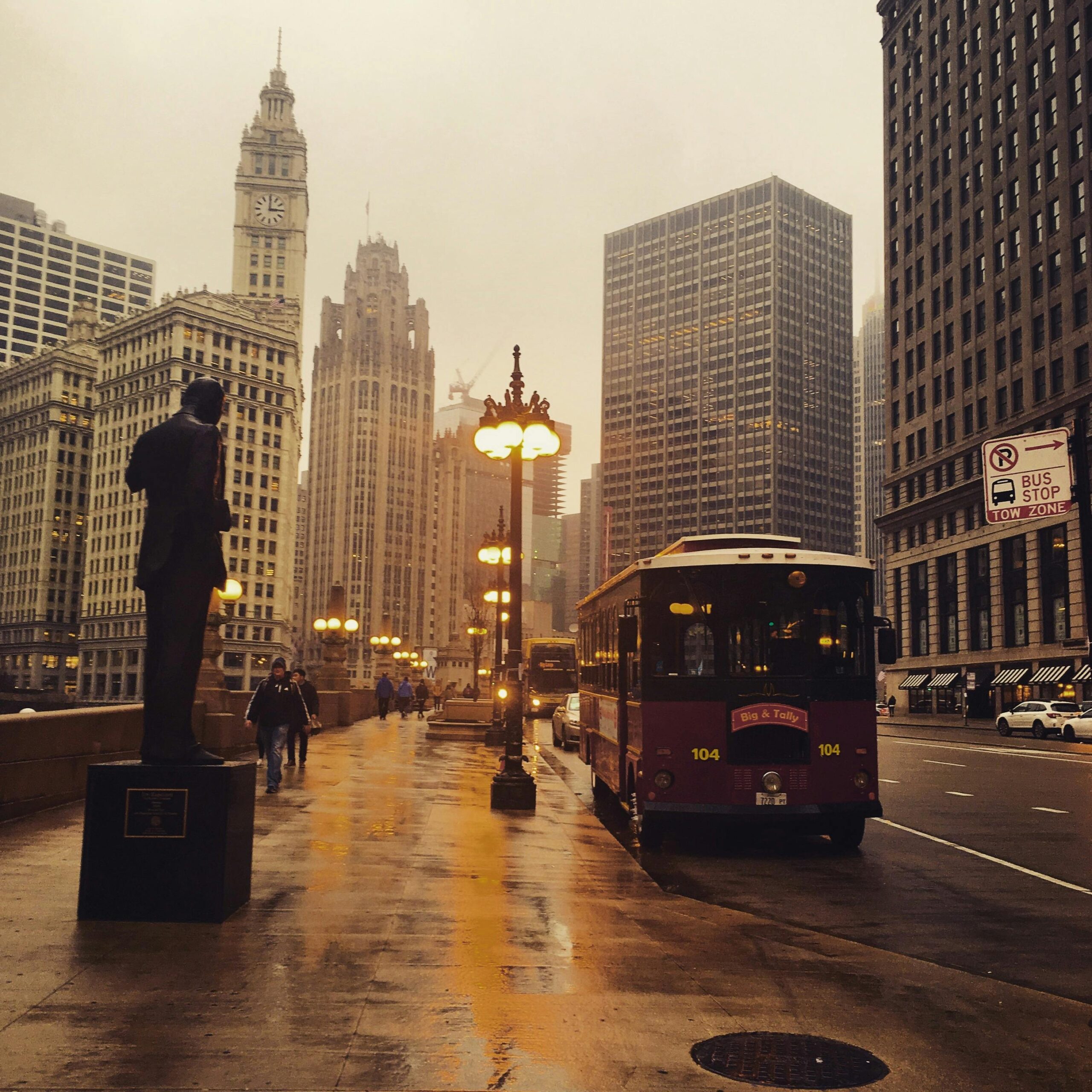 A rainy day scene in downtown Chicago featuring urban architecture, a bus, and the city skyline.