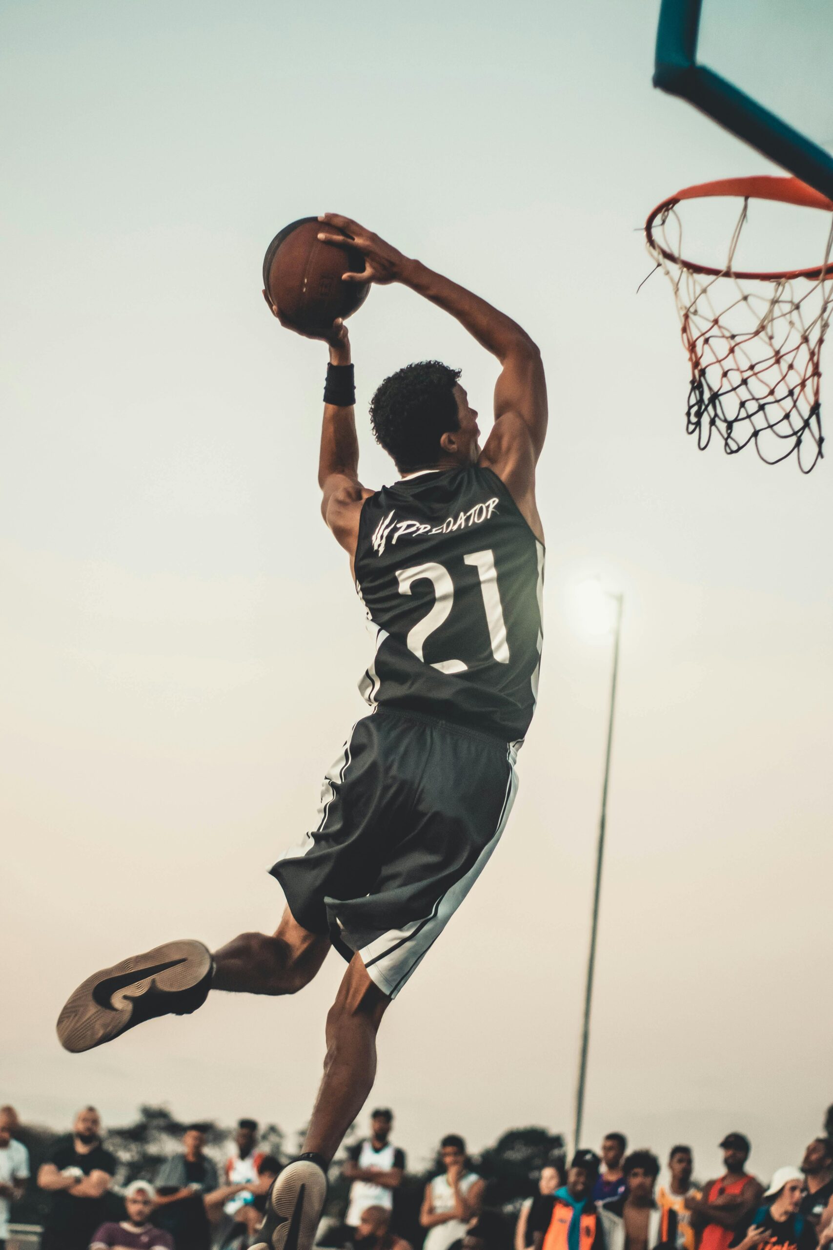 A dynamic basketball player executing a slam dunk during a vibrant outdoor game.