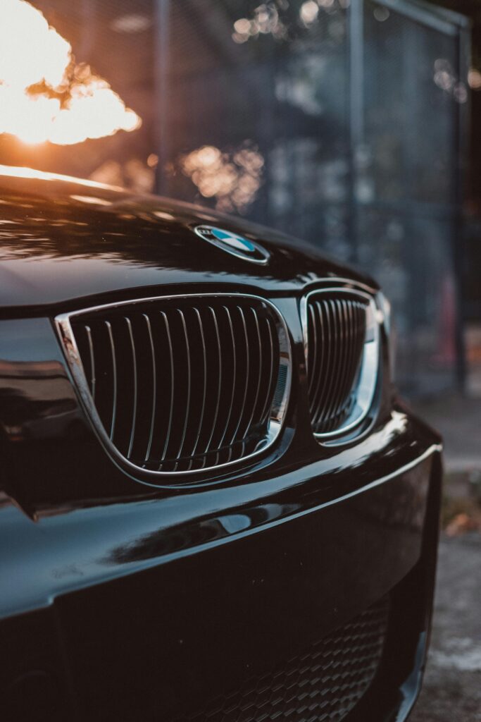 Stylish luxury car grille in focus with sunset reflections, showcasing automotive elegance.